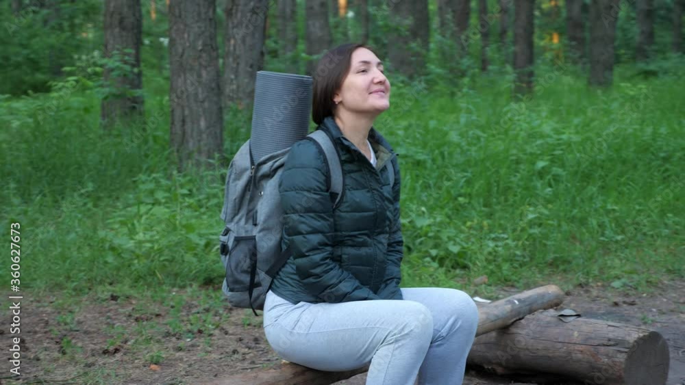 Happy woman with backpack sitting on a log in the forest. Happy woman with backpack sitting on a log in the forest.