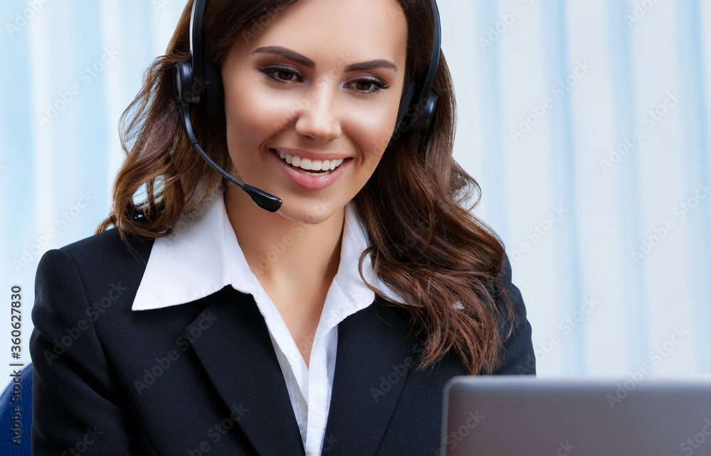 Customer support female phone operator or sales agent in headset and confident black suit, working with laptop at office workplace. Consulting and assistance service call center. Customer support female phone operator or sales agent in headset and confident black suit, working with laptop at office workplace. Consulting and assistance service call center.
