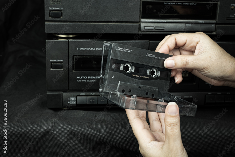 Fototapeta premium Close up women hand holding a cassette tape compact at old played audio tape background
