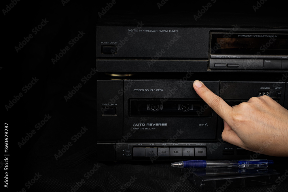 Woman hand inserting compact cassette tape in old player audio are retro technology