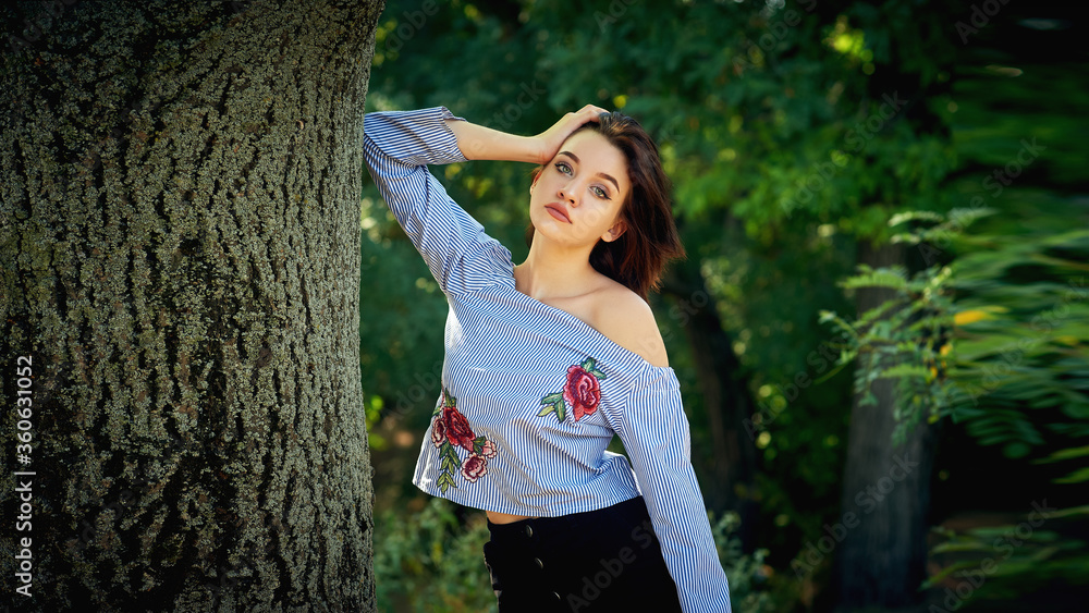 Naklejka premium Portrait of a young beautiful girl close up against a background of green plants