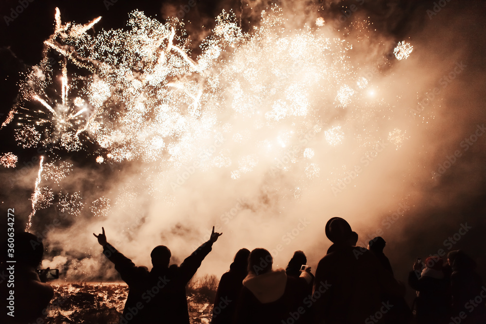 silhouette of joyful people on the background of colorful fireworks with big explosions silhouette of joyful people on the background of colorful fireworks with big explosions