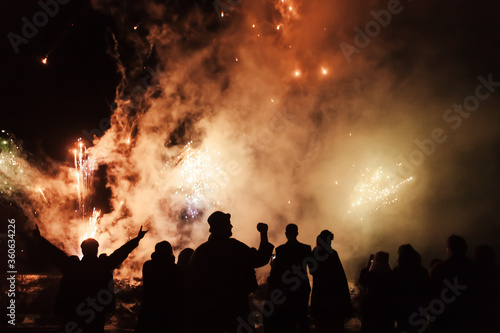 silhouette of joyful people on the background of colorful fireworks with big explosions