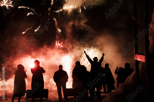 silhouette of joyful people on the background of colorful fireworks with big explosions