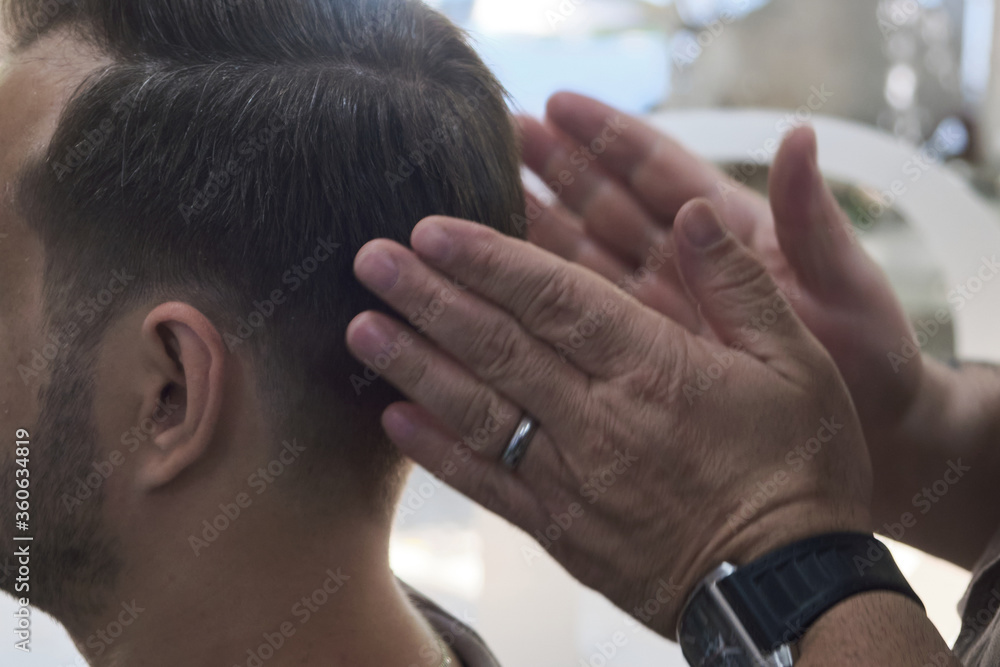 Fototapeta premium Barber does man hair styling after a haircut