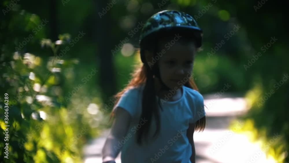 A girl in helmet skating in the park on her rollers A girl in helmet skating in the park on her rollers
