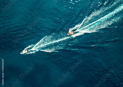 Two motor boats speeding on ocean, aerial top down view