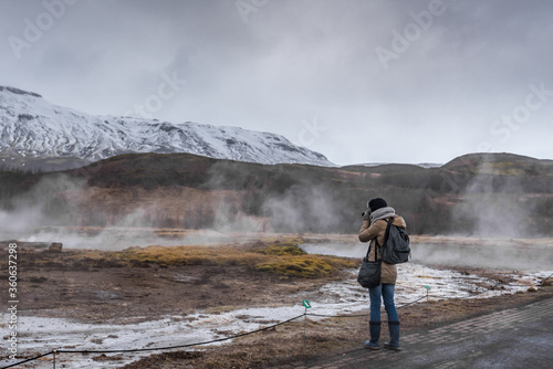 Woman photographing the geysir hotsprings in Iceland, golden circle