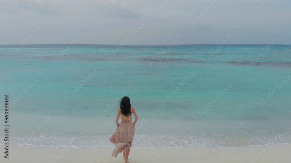 young woman in long skirt walking towards the ocean. Tropical island on coral reef, Paradise of nature. young woman in long skirt walking towards the ocean. Tropical island on coral reef, Paradise of nature.