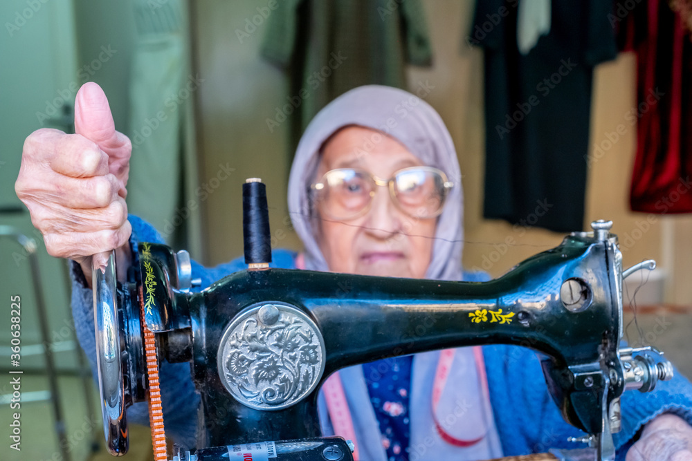 Arabic muslim old woman happy while using sewing machine