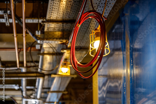 coil of computer network cable hanging from ceiling in front of work light in building under construction