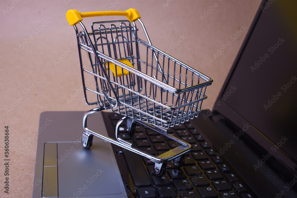 Buy now, Shopaholic on the Internet. Online shopping, shopping cart on laptop keyboard.