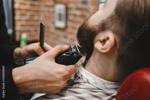 Barbershop beard cutting process. Brutal man caring for his beard