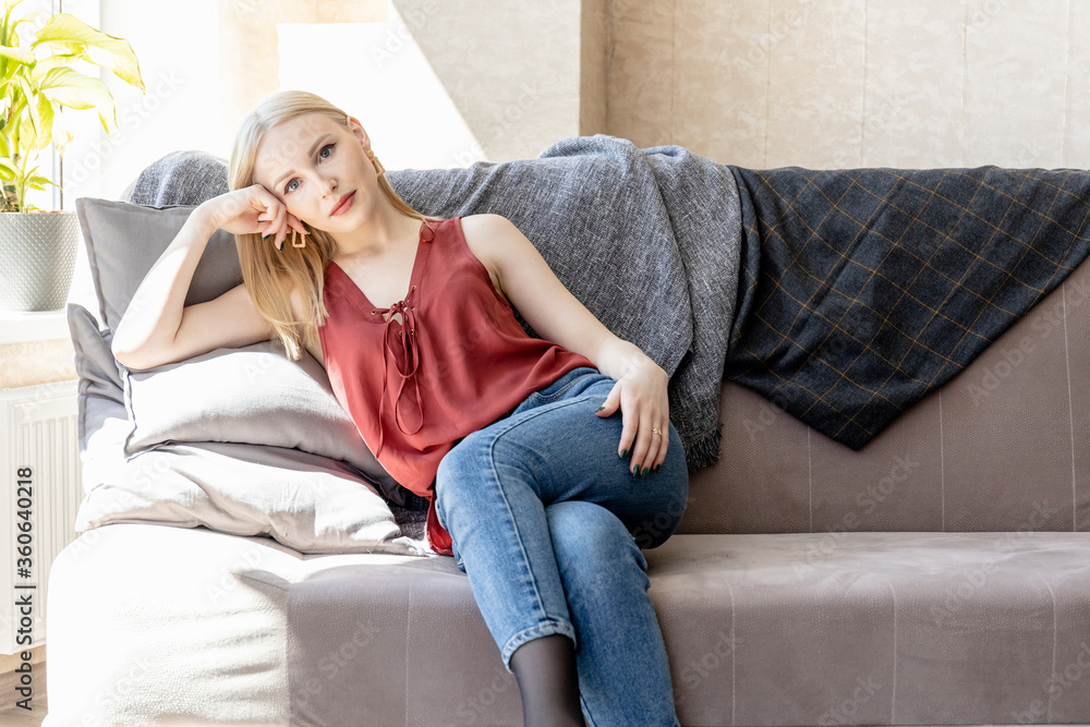 Obraz premium young blonde girl on a sofa in a bright room