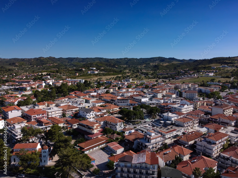Chalkidiki, Greece coastal village landscape drone shot. Aerial view of Hanioti or Chaniotis at Kassandra peninsula with low rise buildings with red tiled roofs.