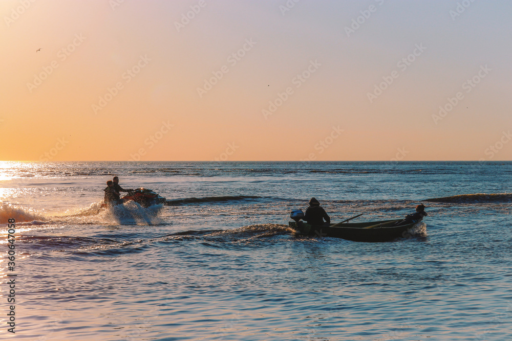 Fototapeta premium fishing at sunset,sea ​​adventures, jet ski, fishermen, spray of water, on the waves