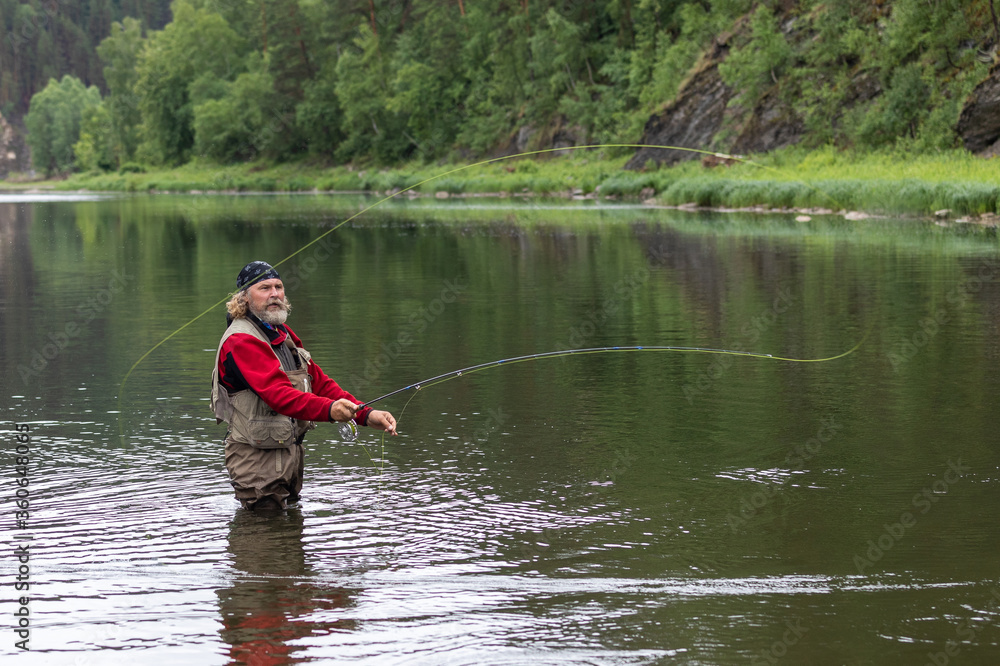 fisherman standing in the water catches a fish. Cast (cast) fishing rod fisherman standing in the water catches a fish. Cast (cast) fishing rod