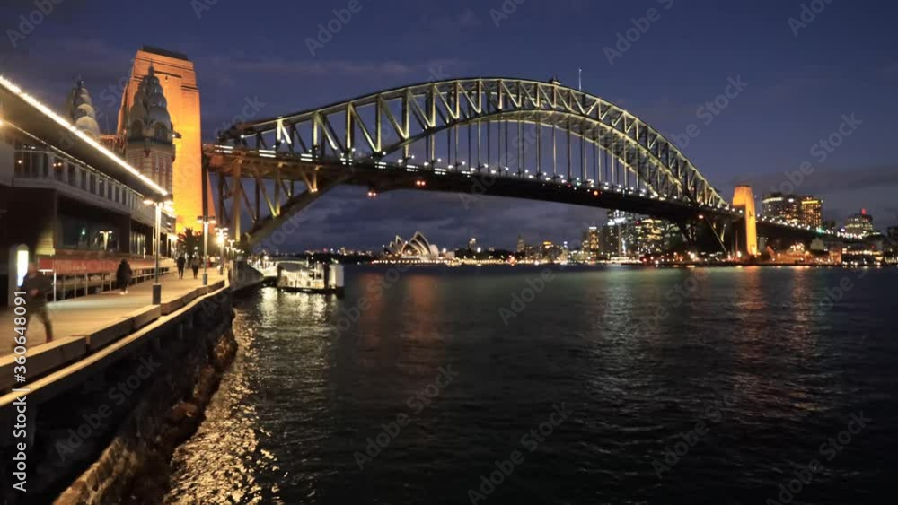Dark sunset around major city Sydney landmarks on waterfront of Harbour – The Bridge and transport ferries.
Dark sunset around major city Sydney landmarks on waterfront of Harbour – The Bridge and transport ferries.