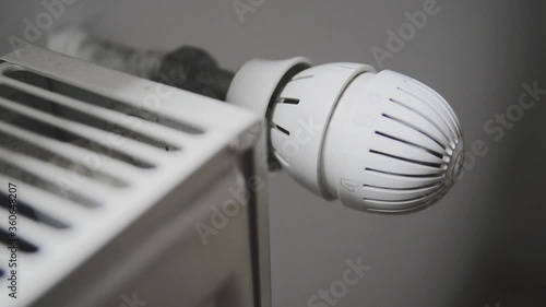 A man changes the temperature using the radiator valve.