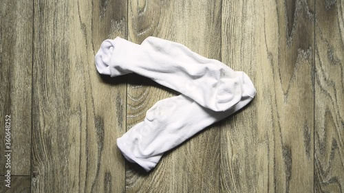 A man takes off his socks and throws them on the floor. Top view.