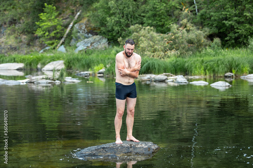 
a person suffering from cold stands on a stone around water and nature