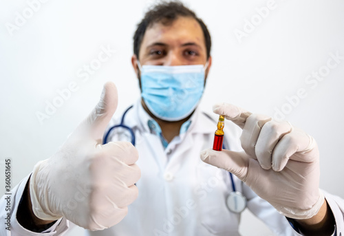 Arabic muslim doctor holding vaccine in his hand