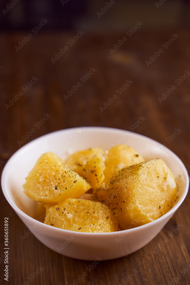 Boiled potatoes with mslom seasonings in a plate on a brown background Boiled potatoes with mslom seasonings in a plate on a brown background