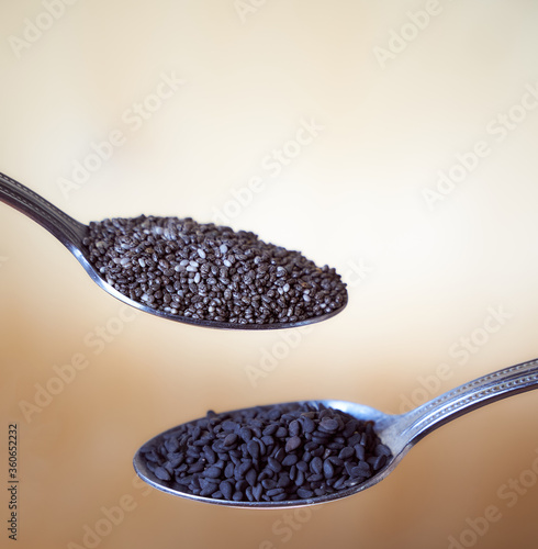 Chia seeds and black sesame seeds in spoons. Light background. Close-up
