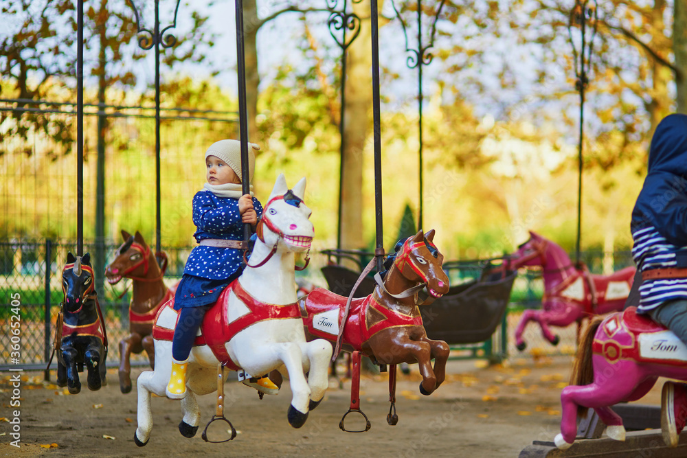 Toddler having fun on vintage French merry-go-round in Paris