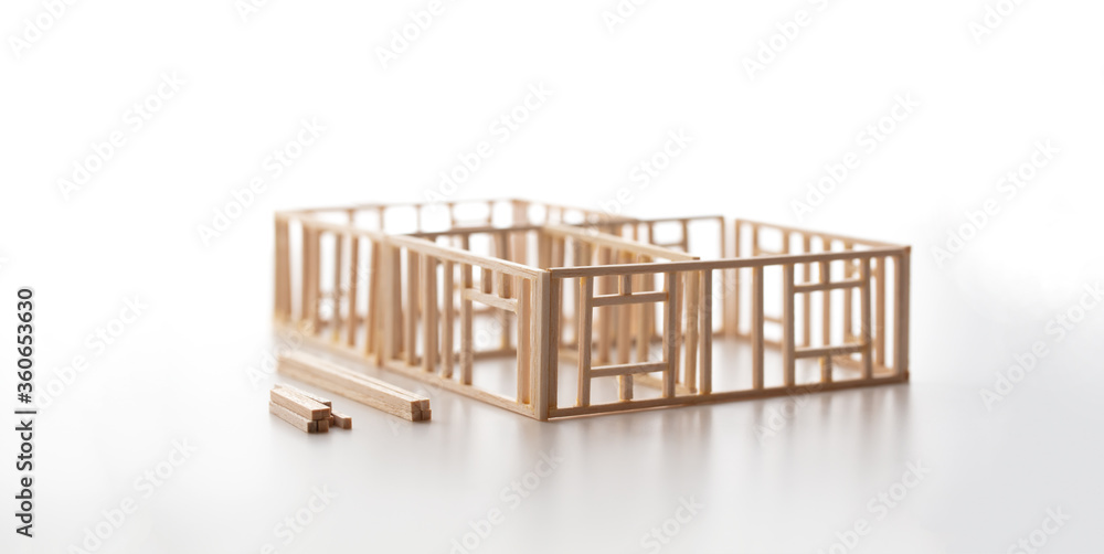 Building a house or a home. Frame work of a house (miniature model) isolated on neutral white with natural shadows. Building a house or a home. Frame work of a house (miniature model) isolated on neutral white with natural shadows.