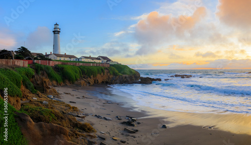 Pastel colors of sunset and silky water from long exposure of waves crashing by Pigeon Point Lighthouse on Northern California Pacific Ocean coastline at sunset