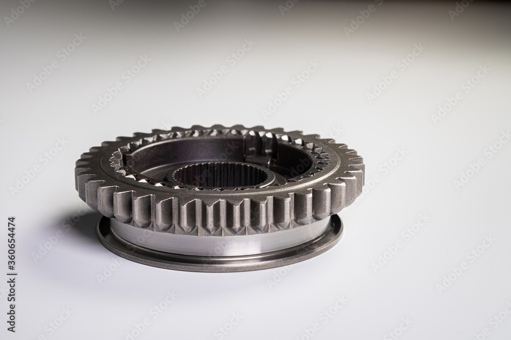 The new shiny metal gear of the switch box is fronted by a gray gradient background. The concept of new spare parts for car maintenance and repair The new shiny metal gear of the switch box is fronted by a gray gradient background. The concept of new spare parts for car maintenance and repair