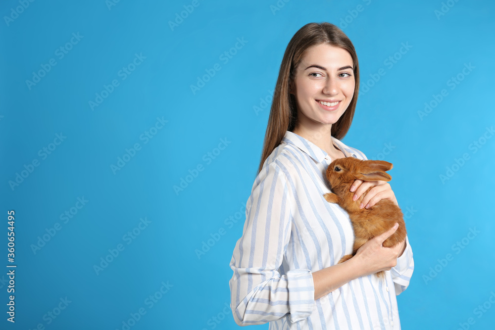 Young woman with adorable rabbit on blue background, space for text. Lovely pet Young woman with adorable rabbit on blue background, space for text. Lovely pet