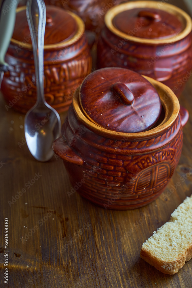 Homemade food. Potatoes and fish in clay pots on a wooden table Homemade food. Potatoes and fish in clay pots on a wooden table