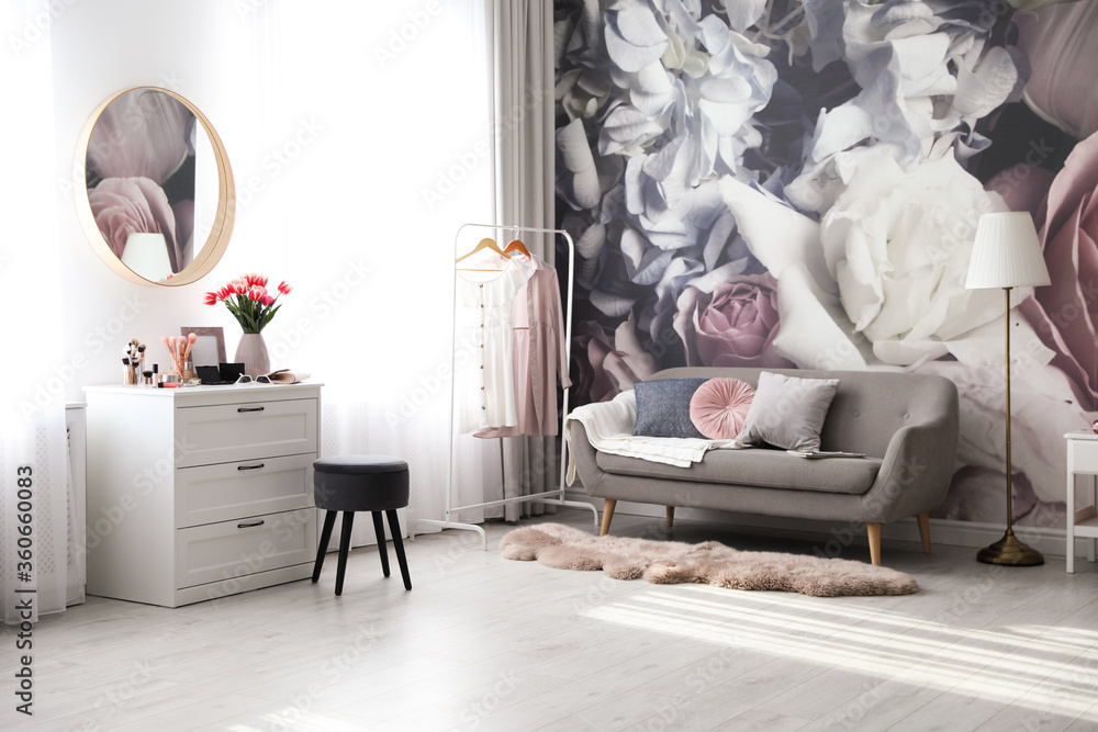 Stylish room interior with dressing table, mirror, sofa and floral