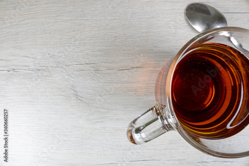 Glass transparent cup with black tea with a top view.