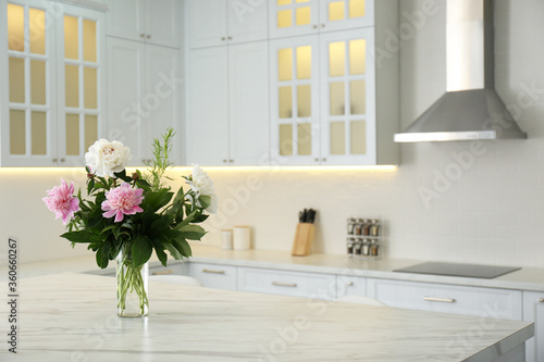 Peony bouquet on white marble table in kitchen interior