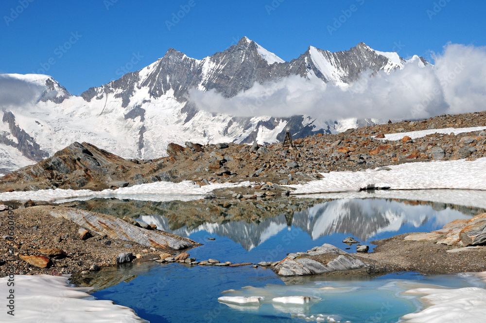 Icy lake reflecting the Mischabel ridge at Hohsaas.