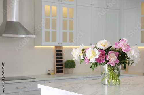 Bouquet of beautiful peonies on table in modern kitchen. Interior design