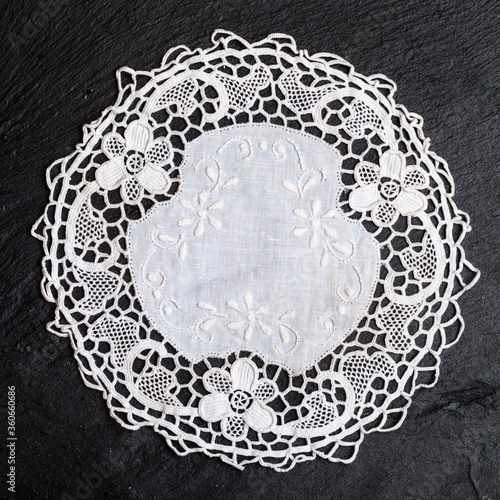 Vintage knitted napkin. White handmade knitted coaster lace doily on a black background.
