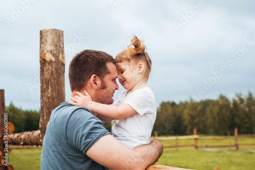 Father andbeautiful baby girl in the village. Sitting high on a wooden fence. Daughter hugs and kisses her father. tender happy family. father's day. photo