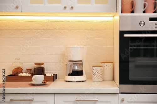 Photo Modern coffeemaker on countertop near brick wall in kitchen