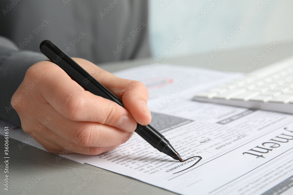 Woman marking advertisement in newspaper, closeup. Job search concept Woman marking advertisement in newspaper, closeup. Job search concept