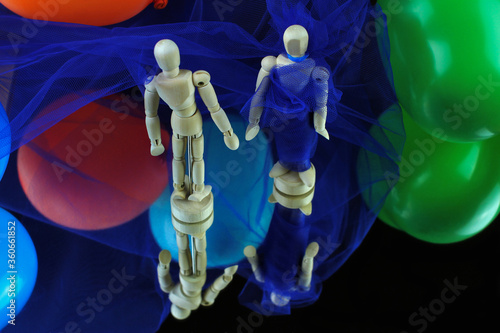 Pair of mannequins from above. She with blue toulle dress walking along a catwalk. Blue background and colorful balloons. photo