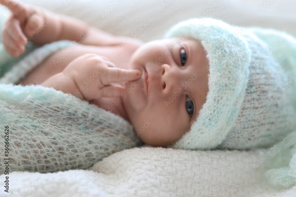 Cute newborn baby in warm hat lying on white plaid, closeup Cute newborn baby in warm hat lying on white plaid, closeup