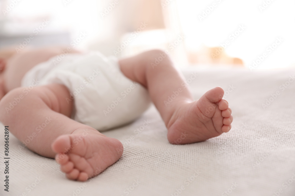 Cute little baby in diaper lying on bed in room, closeup Cute little baby in diaper lying on bed in room, closeup