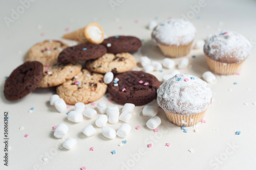 Chocolate brownies, chocolate chip cookies, sprinkled cupcakes and marshmallows on a light background. Sweets on the table