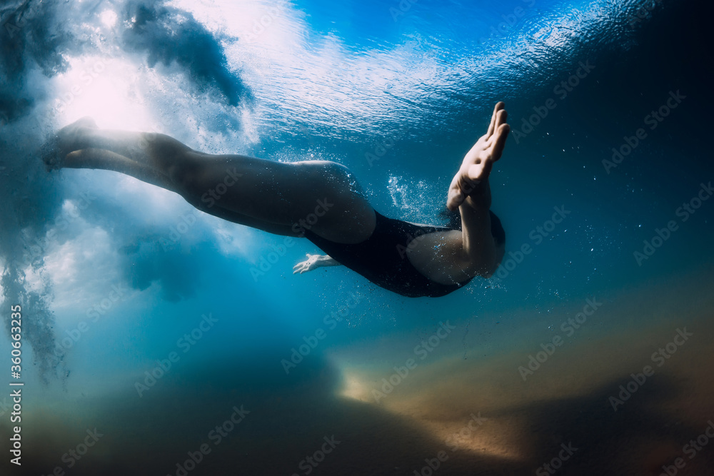 Woman dive without surfboard under wave. Underwater duck dive under wave and sandy bottom