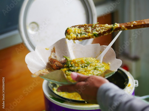 Person taking Menado porridge with wood spoon and takes a spoonful. Menado porridge for breakfast. Indonesian traditional food. photo