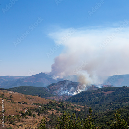 wildfires with mountain and dry grass road leading to fire with smoke